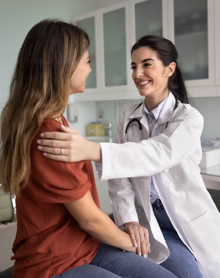 A female doctor comforting and reassuring a young female patient