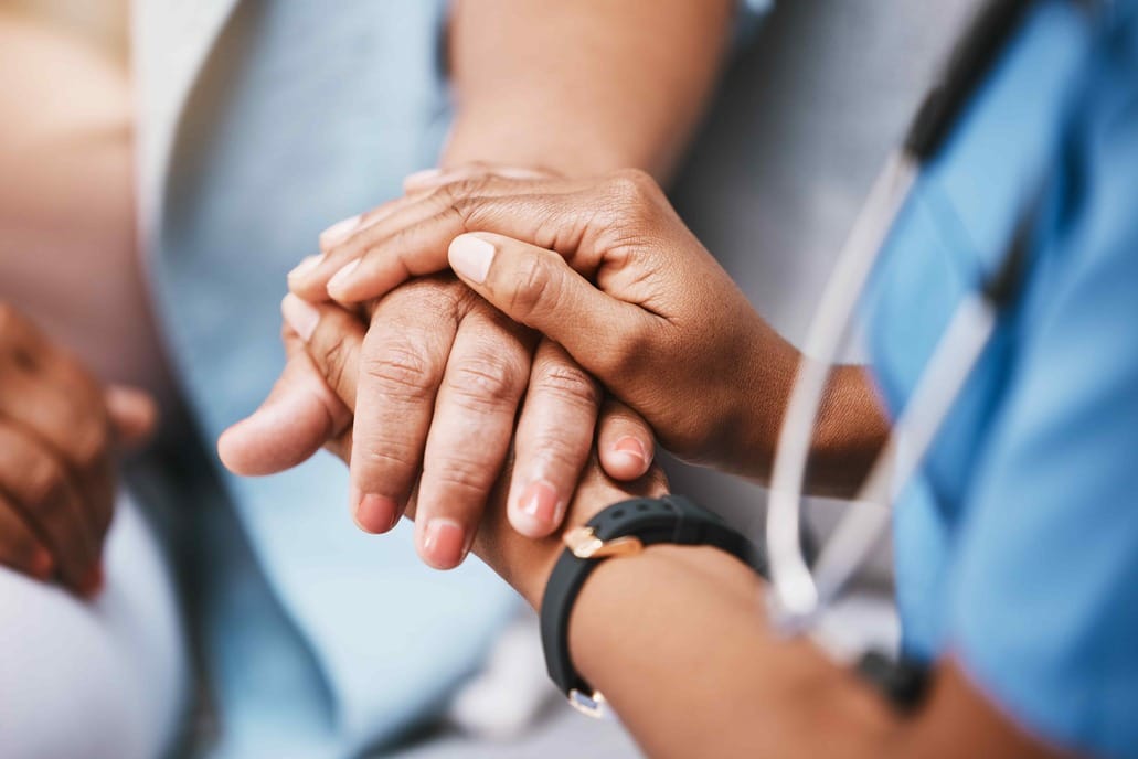 Doctor holding hand of patient in a comforting manner