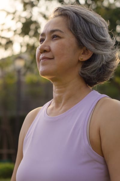 Smiling asian woman looking into the distance, empowered, soft sunlight in background