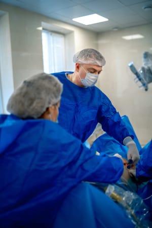 A closeup of two physician's assistants in scrubs helping perform surgery in the operating room