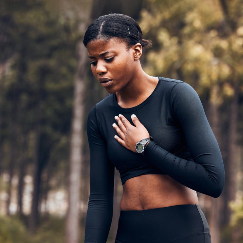 A young female in exercise attire with her hand on her chest and clearly out of breath