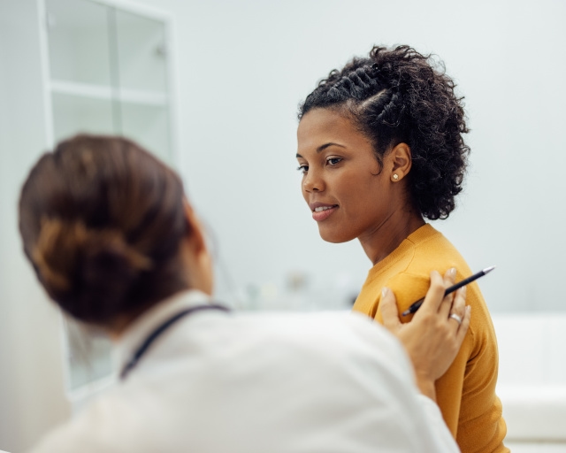 A young woman sitting with her physician being reassured.